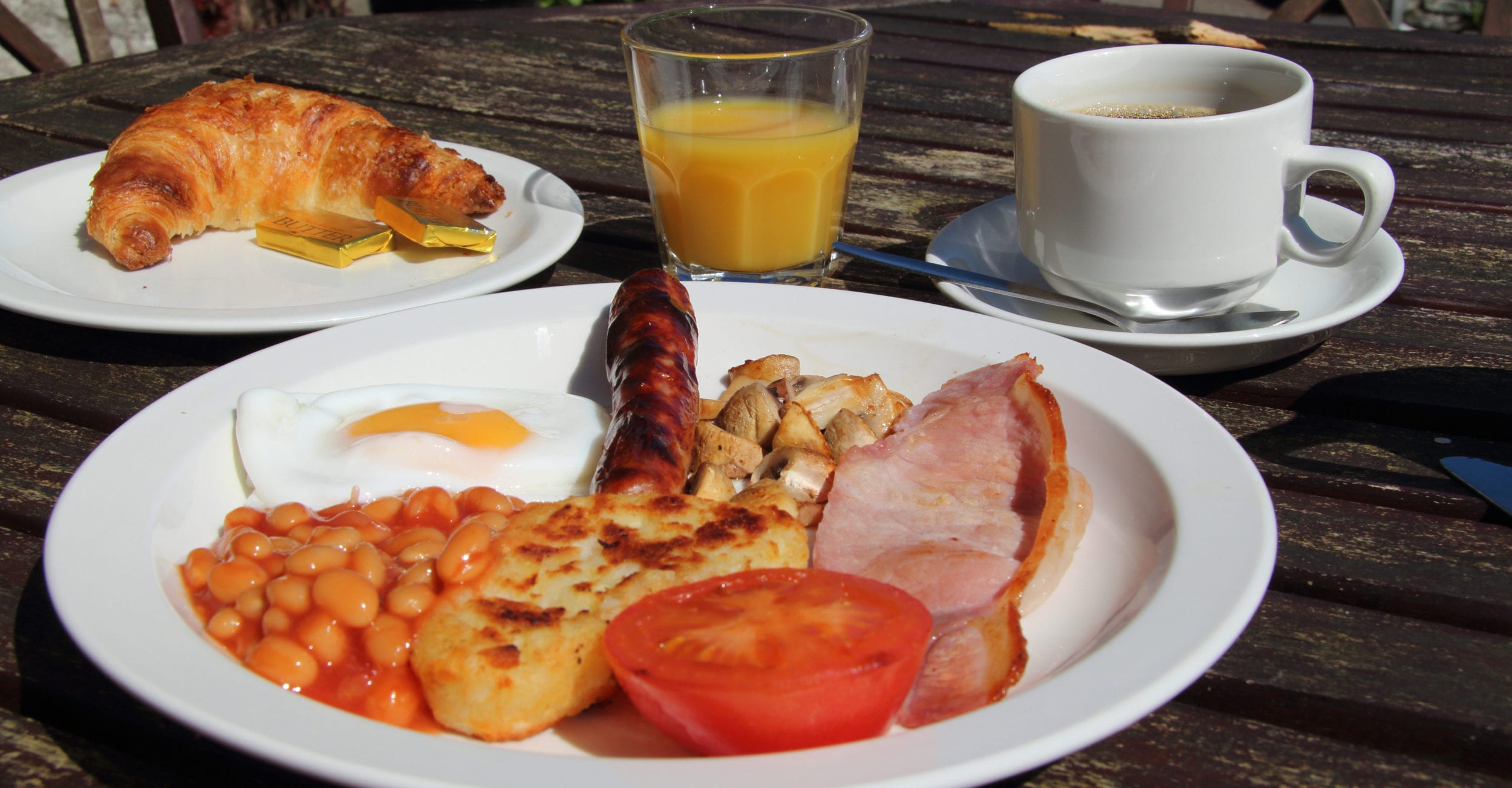 A picture of a english breakfast with bacon, eggs, beans, tomatoes and mushroom 