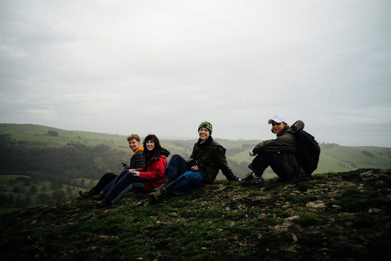 four young people sat on the top of a mountain