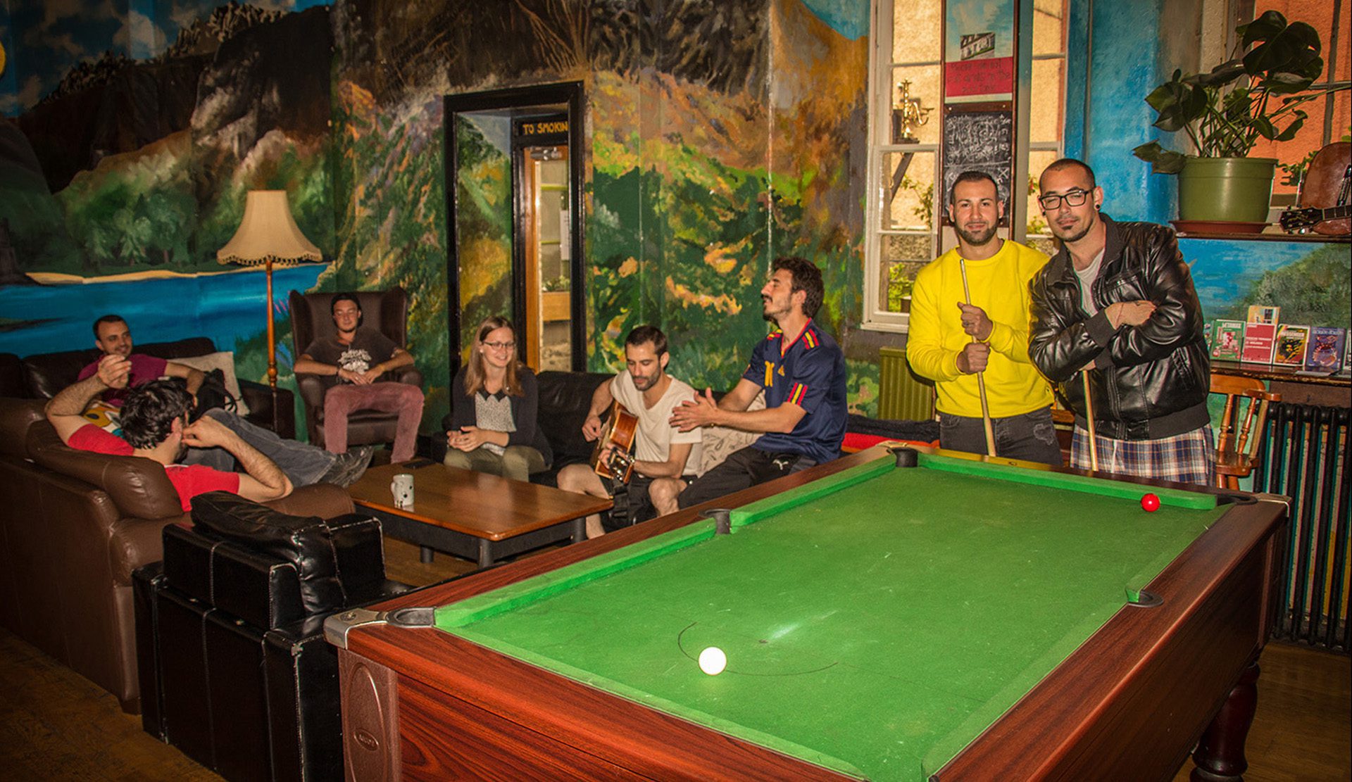 People having fun and making friends and playing pool in the communal area of High Street Hostel in Edinburgh