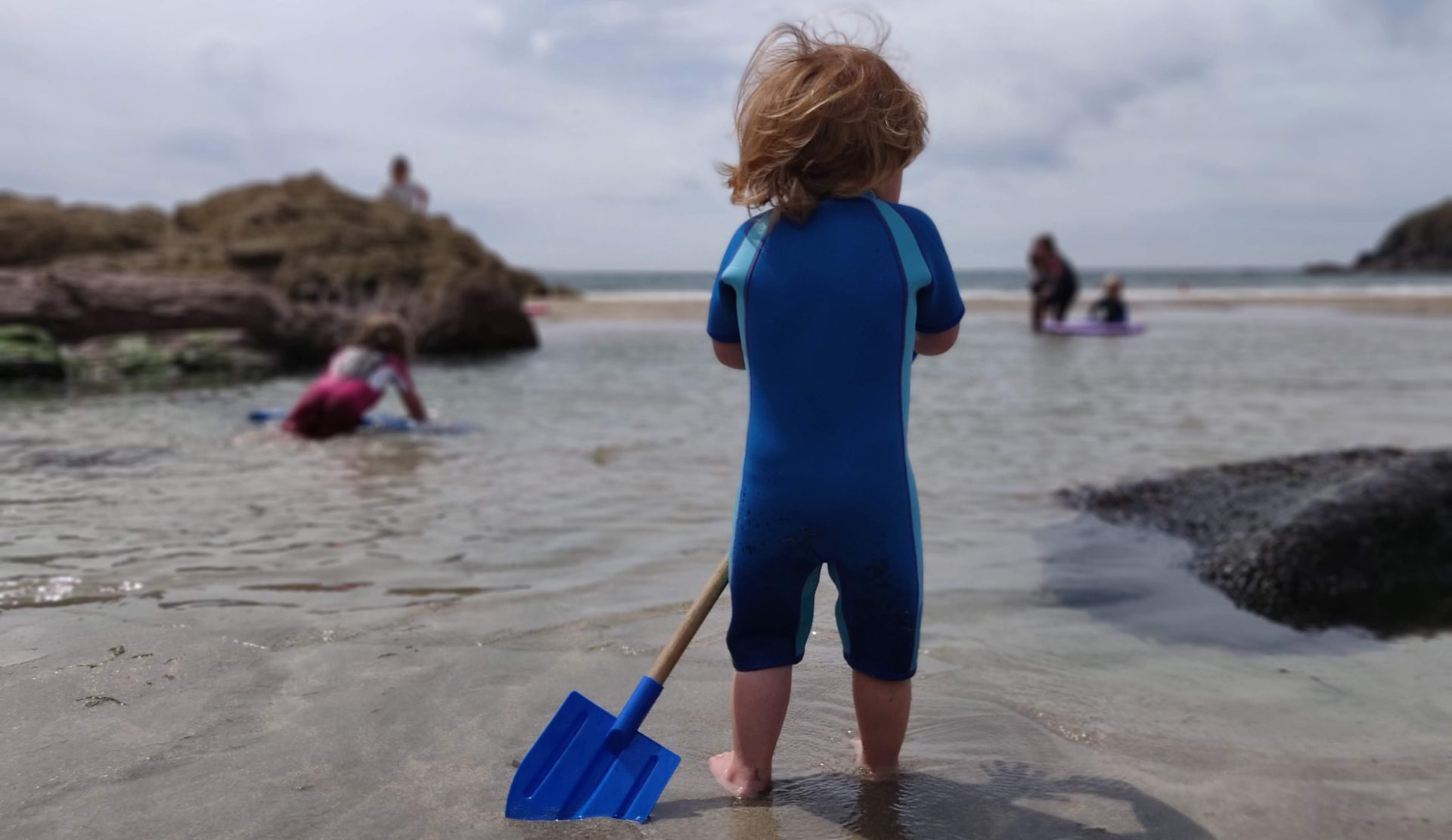 a small child in a three quarter wetsuit enjoying the pembrokeshire coast path beaches 