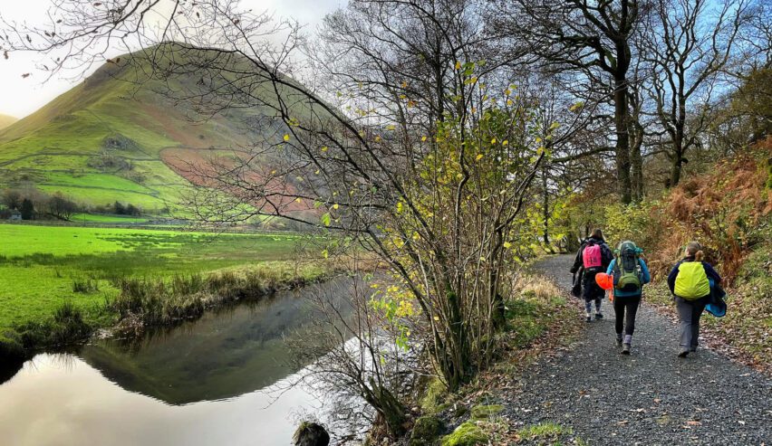 Family with rucksacks on riverside walk from Almond Lodge Helvellyn