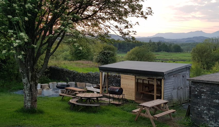 Picnic tables, and summer house with gorgeious views towards field and hills beyond. In the garden at Lowick School Bunkhouse