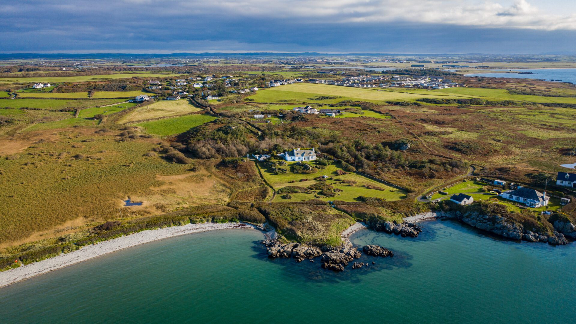 Aerial view of Anglesey coast with white building dotted in the background