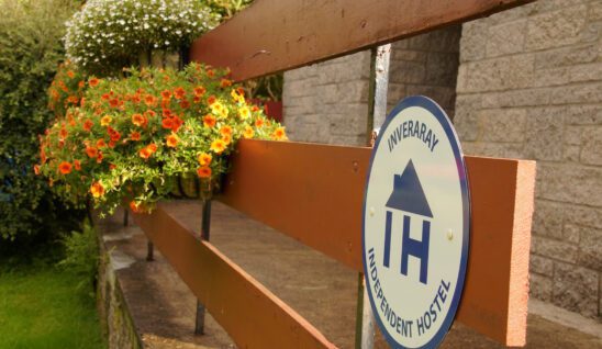 Inveraray Hostel exterior with flowers and a big indepedent hostels sign