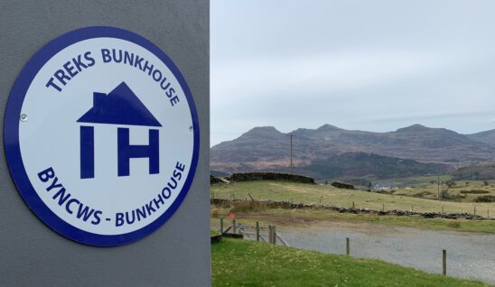 A close up picture of the independent hostel sign on treks bunkhouse with the mountains in the background