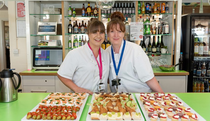 Two smiling cooks in fornt of trays of delicious snacks