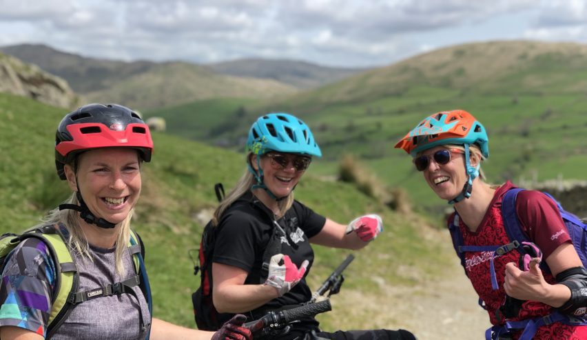 Three brighlty coloured, smiling, lady mountain bikers