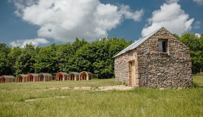 A row of glamping pods with an old stone building in the foreground
