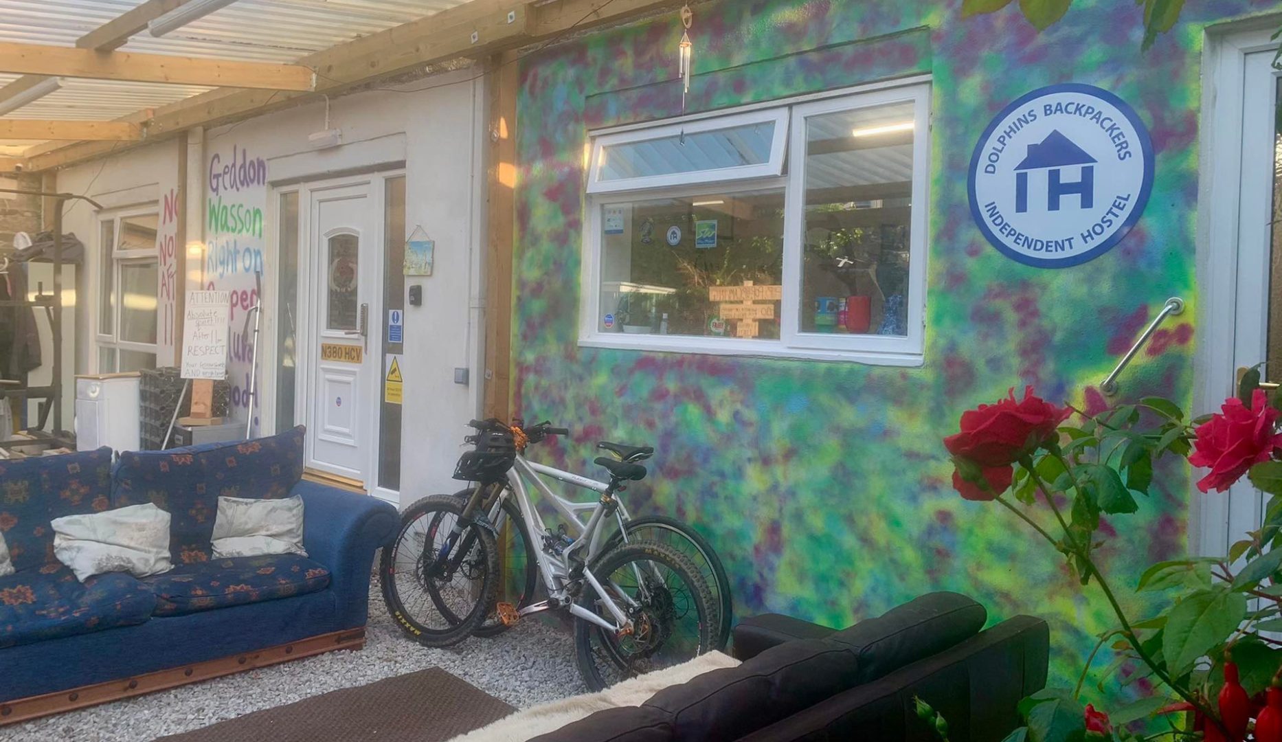 Covered entrance with roed rose, 2 bikes and Independent Hostels sign