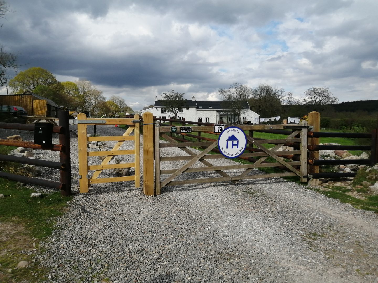 Gate with IHUK sign and white farmhouse down the drive