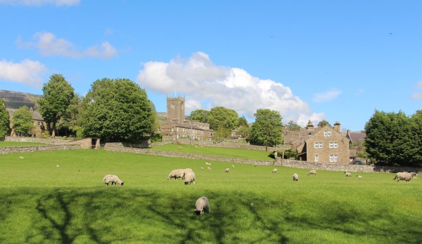 View over sheep pasture to stone church and the village of Askrigg