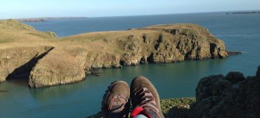 Feet with walking boots with cliffs and sea in the background