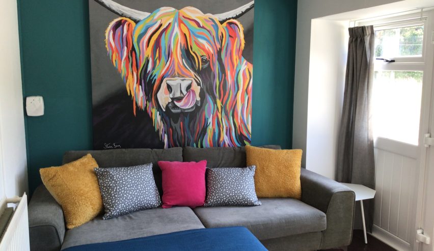Grey sofa under hughe mulit coloured highland cow picture