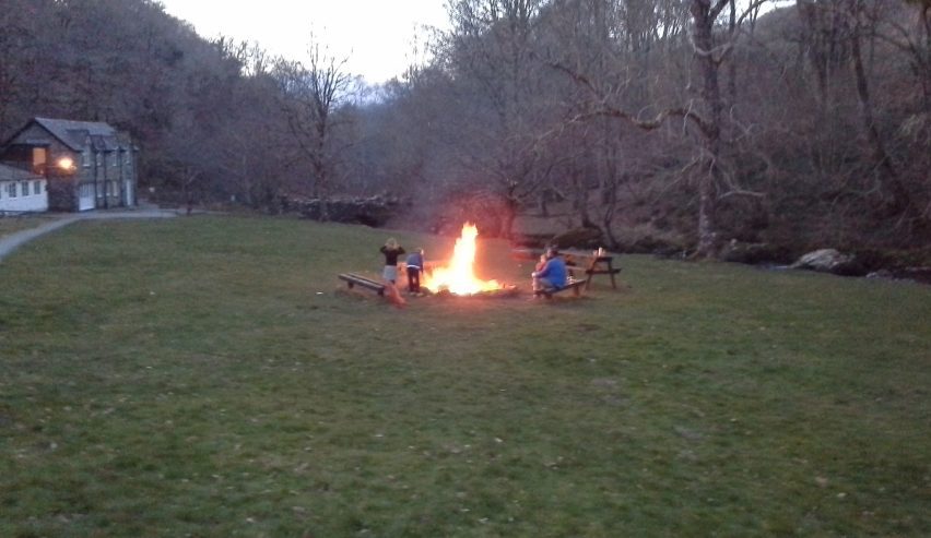 Blazing fire in fire pit with people sitting around it